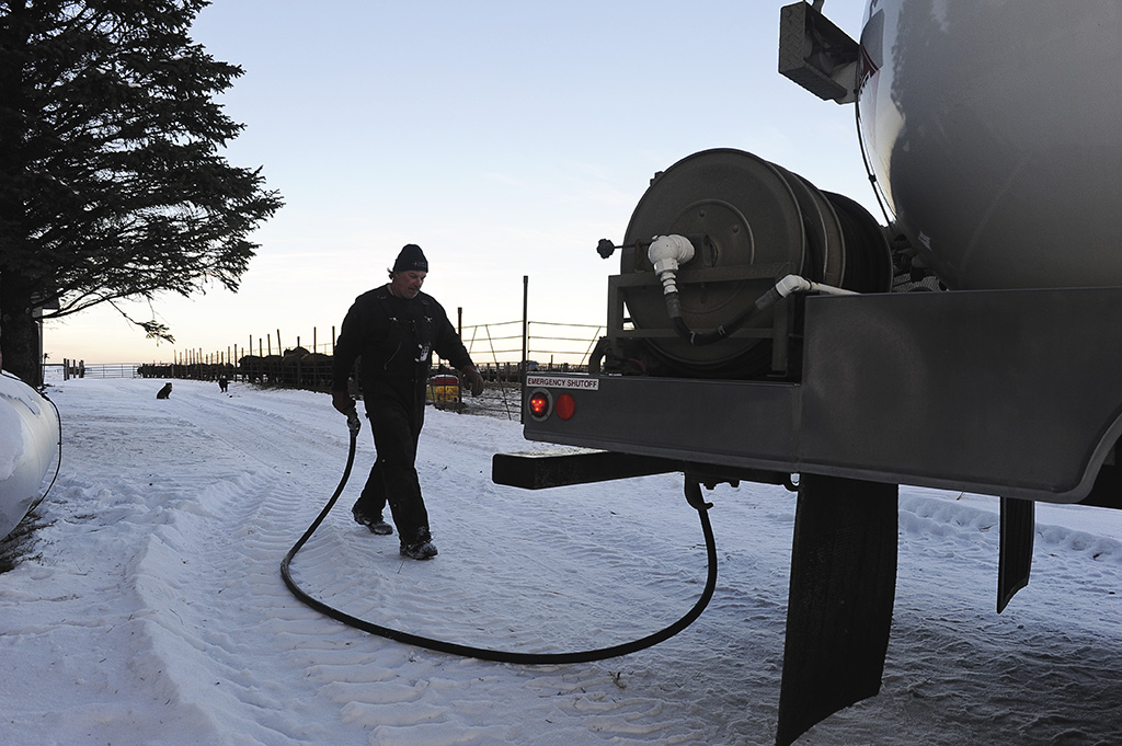 Man walking a hose back from a propane tank to truck