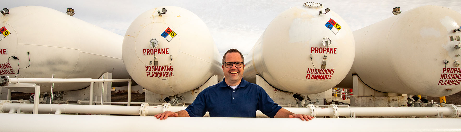 CHS employee standing among propane tanks