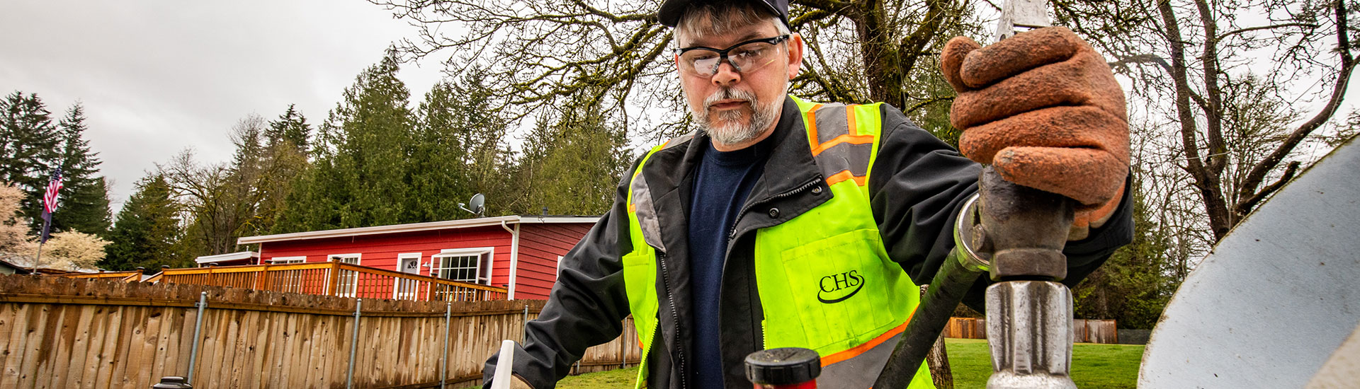 Man with safety vest and glasses filling a propane tank
